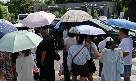 무더위 속 서울 N서울타워를 찾은 외국인 관광객들이 양산을 쓰고 버스를 기다리고 있다. [사진=연합뉴스]