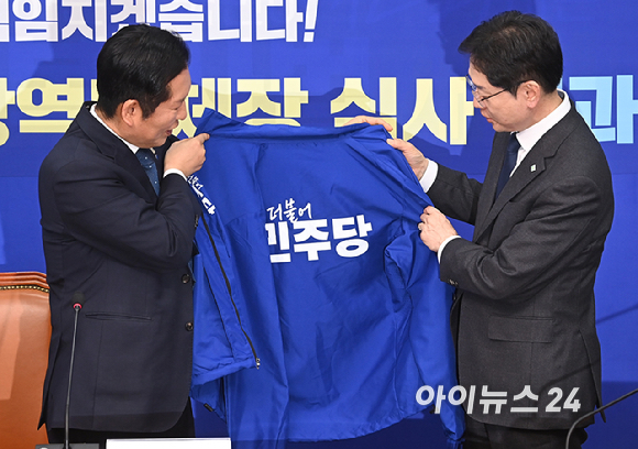 정청래 더불어민주당 대표가 5일 서울 여의도 국회에서 열린 중앙당공천관리위원회 공천 심사 발표에서 경남도지사 후보로 확정된 김경수 지방시대위원장에게 선거복을 입혀주고 있다. [사진=곽영래 기자]