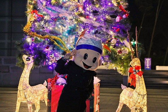 경주타워 앞에 세워진 크리스마스트리를 배경으로 화랑 인형 탈을 쓴 공원직원이 기념사진을 찍고 있다. [사진=경주엑스포대공원]