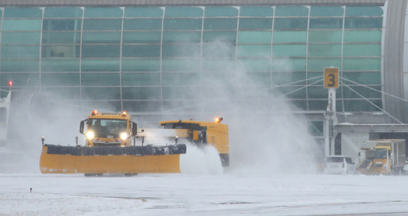 지난해 폭설로 운항이 중단된 제주국제공항 활주로에서 제설차가 쌓인 눈을 치우고 있다.  [사진=뉴시스]