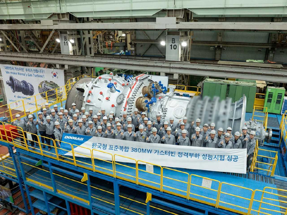 두산에너빌리티 창원 본사에 구축한 가스터빈 전용 시험장에서 개최된 380MW급 가스터빈 정격부하 성능시험 성공 기념식에서 정연인 부회장, 손승우 파워서비스BG장 등 주요 임직원이 기념사진을 촬영하고 있다. [사진=두산에너빌리티]