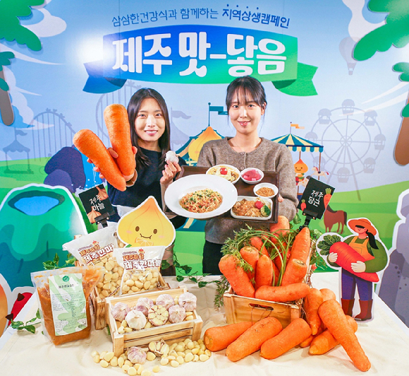 현대그린푸드 직원들이 제주산 당근과 남도종 마늘을 활용해 만든 이색 급식 메뉴인 '당근명란오일파스타'와 '마늘소스 허브닭구이'를 소개하고 있는 모습. [사진=현대그린푸드]