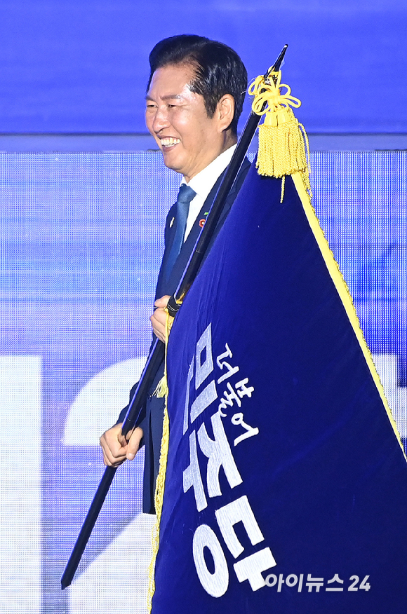 정청래 더불어민주당 신임 대표가 2일 경기 고양시 킨텍스에서 열린 제2차 임시전국당원대회에서 김병기 당대표 직무대행 겸 원내대표로부터 당기를 이양받고 있다. [사진=곽영래 기자]