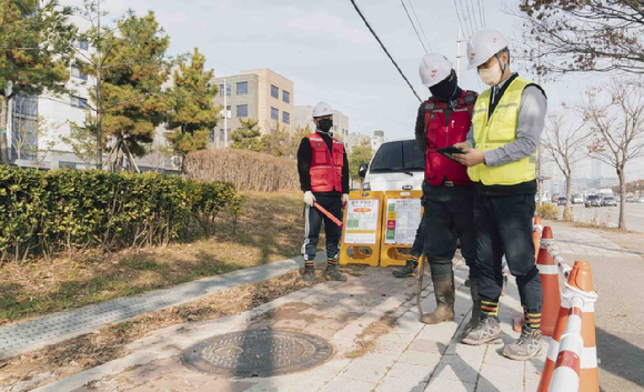 SK텔레콤과 SK오앤에스 작업자들이 IoT 센서로 측정한 맨홀 내부 정보를 스마트폰으로 확인, 작업을 진행하는 모습. [사진=SKT]