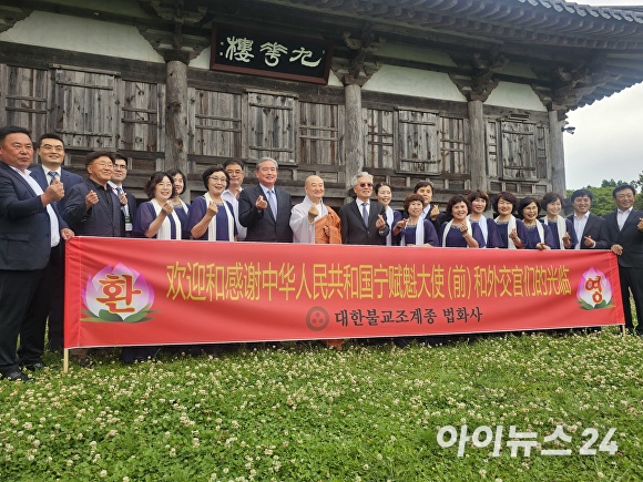 중국방문단 일행과 법화사의 신도와 합창단이 구화루 앞에서 구품연지를 바라보며 사랑의 하트를 날리고 있다. [사진=박태진 기자]