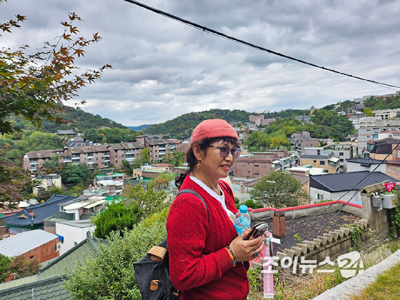 장문자 작가가  19일 서울 종로구 부암동 백사실 계곡에서 진행된 '스타 고우리와 함께 하는 제10회 희망찾기 등산·트레킹 교실'에 참여했다. 고즈넉한 마을을 배경으로 사진 촬영을 하고 있다. [사진=이미영 기자]