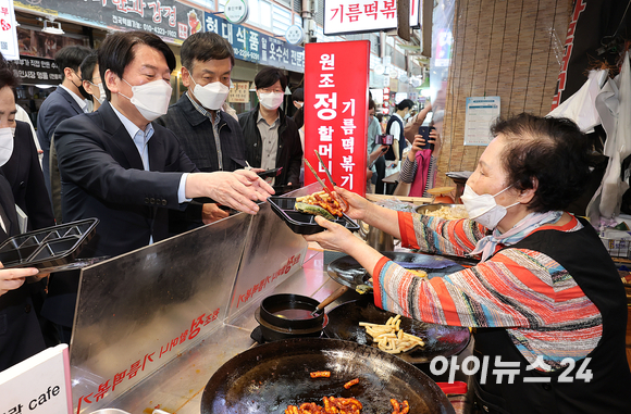 안철수 대통령직인수위원회 위원장(왼쪽)이 10일 서울 종로구 통인시장을 방문해 엽전을 이용해 기름떡볶이를 구매하고 있다. [사진=김성진 기자]