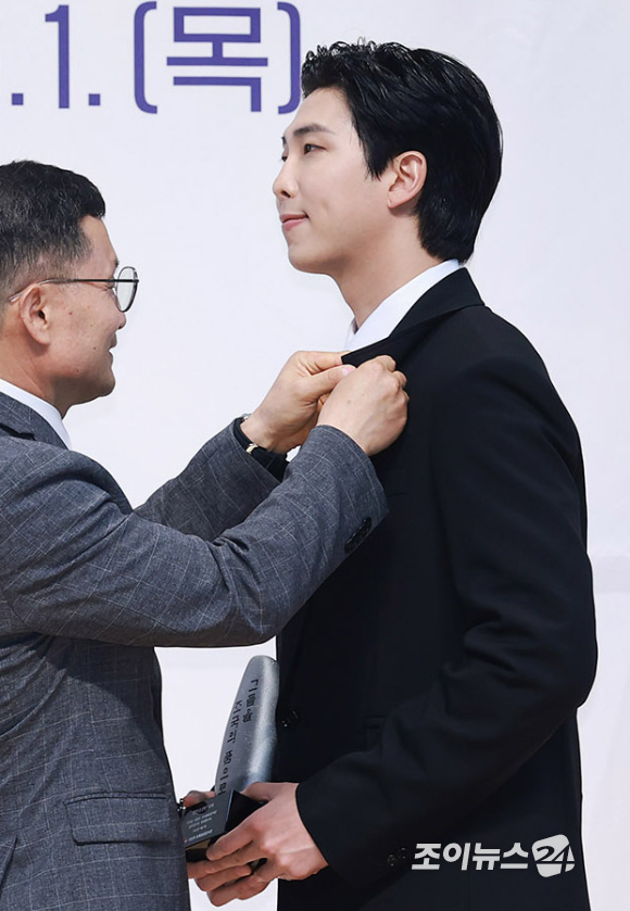 그룹 방탄소년단 리더 RM(본명 김남준)이 1일 오후 서울 동작구 국립서울현충원 현충관에서 열린 2023 국방부 유해발굴감식단 홍보대사 위촉식에서 이근원 단장으로부터 배지를 수여받고 있다. [사진=사진공동취재단]