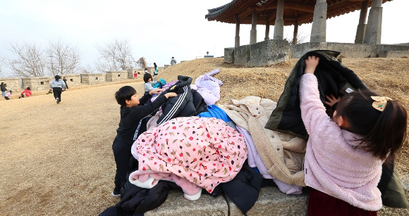 포근한 날씨 속 인천 강화군 연미정으로 겨울방학 현장체험학습을 나온 어린이들이 두꺼운 외투를 벗어놓고 있다. [사진=연합뉴스]