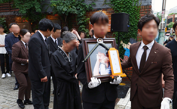 24일 서울 대학로 아르코꿈밭극장에서 고(故) 김민기 전 학전 대표의 유가족들이 고인의 영정과 함께 운구차로 향하고 있다. [사진=뉴시스]