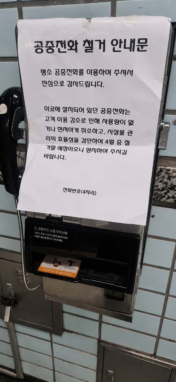 지하철 역사에 설치된 공중전화에 이용 감소를 이유로 철거를 알리는 안내문이 붙어 있다. 사번번호 등 개인정보 보호를 위해 일부 내용은 AI로 가렸다 [사진=서효빈 기자]