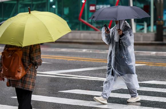 서울 강남구 강남역 인근에서 한 시민이 우비를 입은 채 우산을 들고 이동하고 있다. [사진=뉴시스]