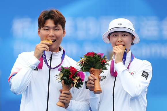 4일 중국 항저우 푸양 인후 스포츠센터에서 열린 2022 항저우 아시안게임 양궁 혼성 리커브 결승 일본과의 경기 후 시상식에서 이우석과 임시현이 금메달을 입에 물고 기념촬영 하고 있다. [사진=뉴시스]