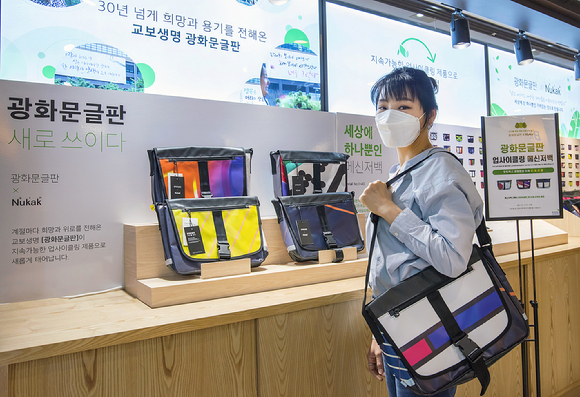 서울 종로구 교보핫트랙스 광화문점 팝업스토어에서 한 시민이 광화문글판 업사이클링 메신저 백을 살펴보고 있다. [사진=교보생명]