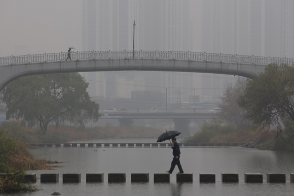 경기도 의정부시 중랑천에서 시민들이 우산을 쓰고 이동하고 있다. [사진=연합뉴스]