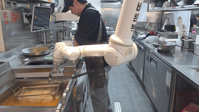 관절형 로봇이 움직이며 치킨을 조리하고 있다. [사진=구서윤 기자]