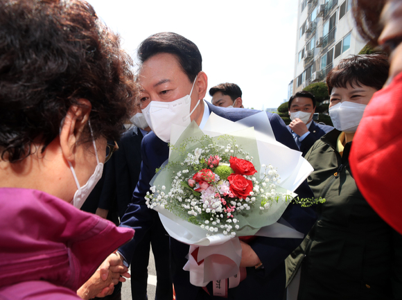 윤석열 대통령 경기 안양시 동안구 소재 1기 신도시 노후아파트를 방문 주민에게 꽃을 받고 있다. [사진=인수위사진기자단]