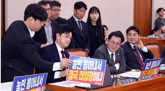 7일 국회에서 열린 농림축산식품해양수산위원회 국정감사에서 국민의힘 위원들이 "농민 몰아내서 결국 태양광이냐"라고 쓰인 피켓을 앞에 걸었다가 더불어민주당 위원들의 요구에 떼어내고 있다. [사진=연합뉴스]