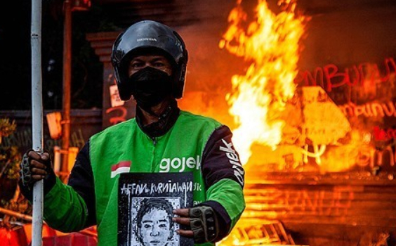 한 인도네시아 시민이 경찰차에 분노의 발길질을 날리고 있다. [사진=AP/연합뉴스]