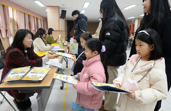 울산지역 초등학교 신입생 예비소집일인 3일 오전 울산 중구 울산초등학교 가입학식에서 예비 초등학생들이 교사로부터 교재를 전달받고 있다. [사진=뉴시스]