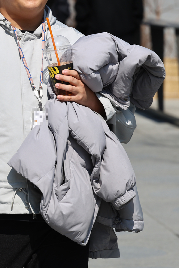 6일 서울 종로구 광화문 네거리에서 반팔 티셔츠를 입은 시민이 외투를 손에 들고 이동하고 있다. [사진=연합뉴스]