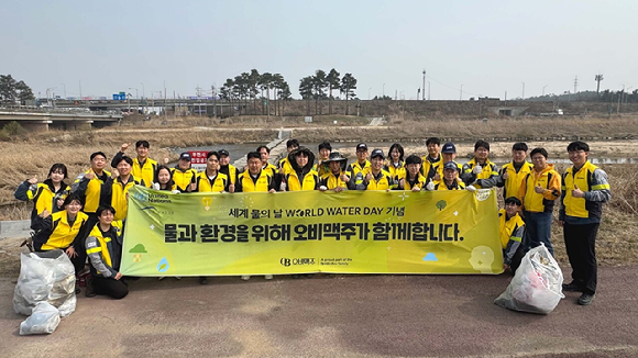 지난 27일 오비맥주 이천공장 임직원이 이천 복하천 일대에서 환경 정화 활동을 마치고 기념사진을 찍고 있다. [사진=오비맥주]