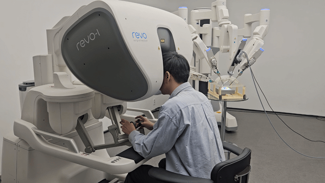 기자가 마스터콘솔에 앉아 암컨트롤러에 연결된 벨트에 엄지와 중지를 넣고 조작을 하고 있는 모습이다. [사진=설재윤 기자]