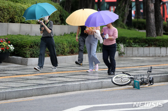 비가 내리는 28일 오후 서울 중구 세종대로 인근에서 우산을 쓴 시민들 옆으로 자전거가 바람에 쓰러져 있다. [사진=뉴시스]